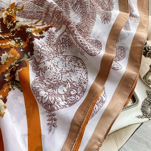 Détail d'un foulard en soie montrant des motifs de feuilles d'érable et un tissu soyeux