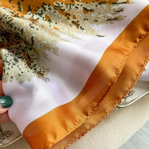 Détail de l'écharpe en soie avec imprimés floraux et bordure orange cousue main