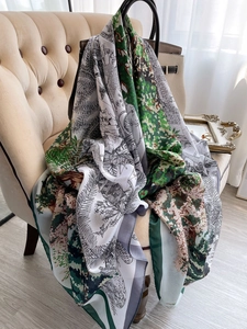 Détail d'un élégant foulard en soie à imprimé forêt drapé sur un fauteuil beige chic