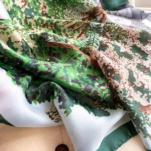 Détail d'un foulard en soie à imprimé forêt vintage avec tissu satiné et bord vert
