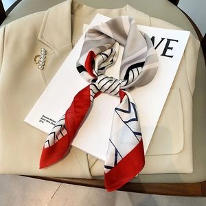 Satin silk scarf with red and grey geometric patterns paired with a pearl brooch