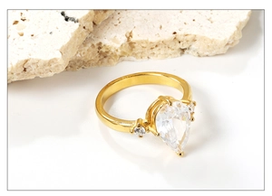 Macro shot of 18k gold plated pear-shaped diamond ring with minimalist side stone setting