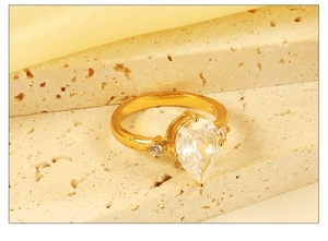 Detail of 18k gold ring with pear-shaped gemstone and side diamonds on stone base