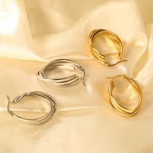 Polished triple-layered 18K gold and silver hoop earrings on champagne silk fabric