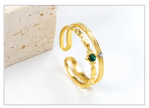 Detail of gold double-layer open ring featuring green gemstone and sparkling zircon