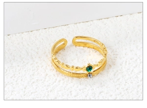 Detail of a 18K gold-plated double-layer open ring with emerald and crystal inlays