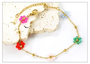 Macro detail of stainless steel bracelet featuring five colorful beaded flowers and lobster clasp
