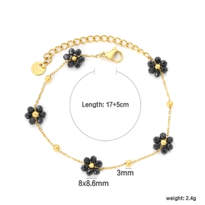 Détail d'un bracelet en acier inoxydable doré avec des breloques fleurs en perles noires