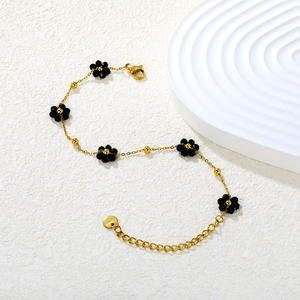 Vue détaillée du bracelet en acier doré orné de délicates fleurs en perles noires facettées