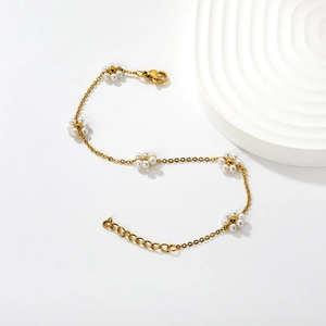Detail of gold chain bracelet featuring five faux pearl flowers and lobster clasp