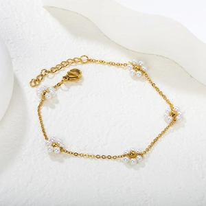 Elegant gold chain bracelet featuring five pearl daisy flowers with adjustable lobster clasp