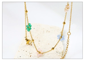 Détail du collier en acier doré avec perles en forme de fleurs colorées en acrylique