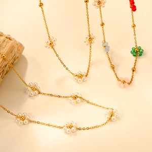 Collier à fleurs en perles d'imitation et chaîne dorée sur un fond de pierre minimaliste