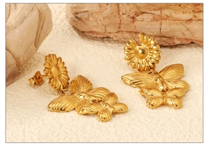 Makroaufnahme von 18K Gold Schmetterling- und Sonnenblumen-Ohrringen auf Steingrund
