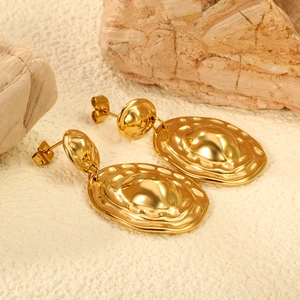 Irregular textured gold stainless steel oval earrings with 18K plating on stone background