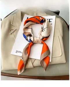 Macro shot of silk-like neckerchief with orange chain print styled on a beige blazer