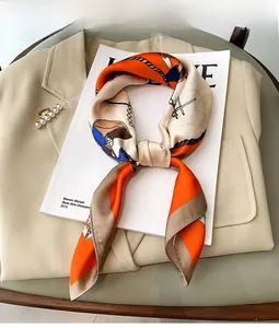 Close-up of equestrian silk scarf with horse bit patterns on chic blazer background