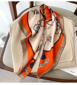 Detail of vintage carriage print silk scarf draped over a neutral blazer and chair