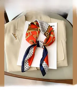 Détail d'un foulard en soie synthétique à motif chaîne sur un blazer beige avec perles