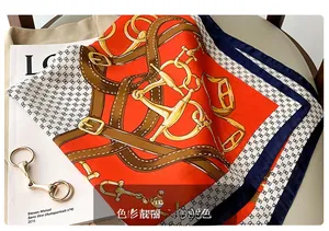 Détail d'un foulard en soie avec imprimé chaîne équestre et boucles dorées