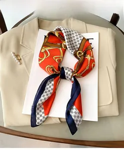 Détail d'un foulard en satin à motif chaîne sur un magazine et un blazer beige