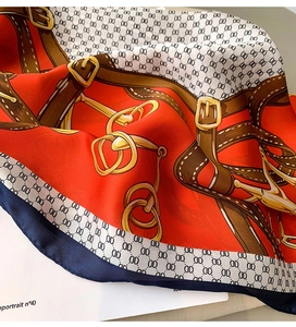 Gros plan sur un foulard en soie avec motif mors doré et imprimé de ceinture rouge