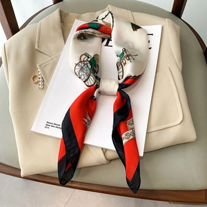 Satin neck scarf with retro chain print and red accents styled on a beige blazer