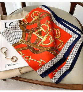 Vue détaillée d'un foulard en soie orange avec motifs de chaînes équestres sur magazine