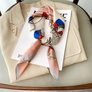 Elegant retro silk scarf with chain and carriage prints tied on a white magazine