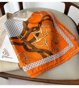 Détails du foulard en soie aux motifs équestres avec tons orange et boucles
