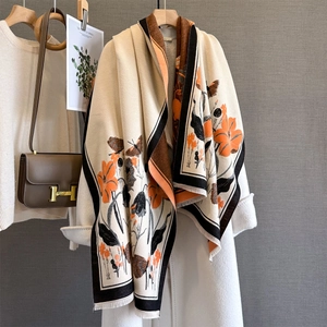 Châle en maille vintage à fleurs orange et pompons sur un manteau en laine beige