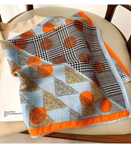 Detail of silk satin scarf with houndstooth and paisley prints on a leather chair