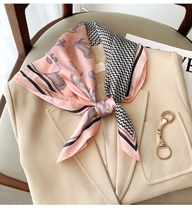 Close-up of pink silk scarf with horse print tied on a beige blazer for a chic look