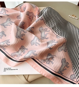 Detail of pink silk-feel scarf featuring grey horse patterns and wavy geometric borders