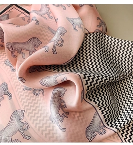 Detailed view of pink silk-like scarf featuring artistic horse prints and wavy edges