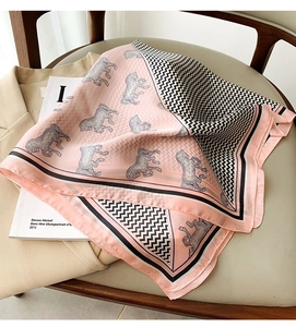 Detail of pink and black silk scarf with artistic horse pattern on beige blazer