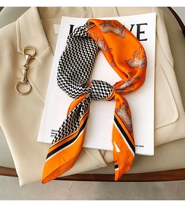 Detail of faux silk scarf with orange horse print and chevron pattern on a beige blazer