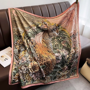 Detail of a jungle print square scarf featuring leopards and monkeys on a leather sofa