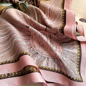 Detail of luxury silk scarf with leopard print and gold chain patterns on pink fabric