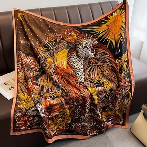 Detail of artistic leopard print scarf with sun and moon motifs on a leather sofa