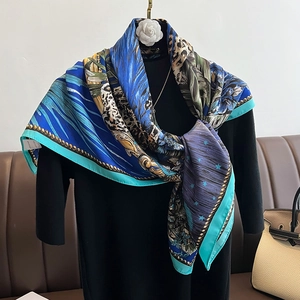 Detailed close-up of blue silk scarf featuring leopard print and tropical floral motifs