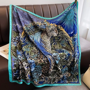 Detail of artistic floral and leopard print satin scarf draped on a leather couch