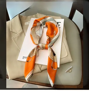 Close-up of bright orange printed silk scarf tied in a bow on a white magazine