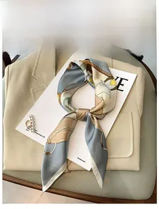 Detail of silk-feel scarf with chain and geometric print on a blazer background