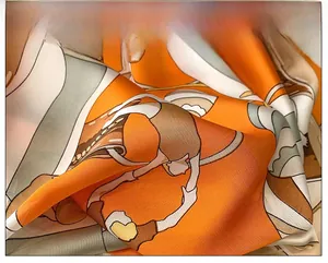 Macro detail of silky orange printed square scarf showing elegant drape and floral pattern
