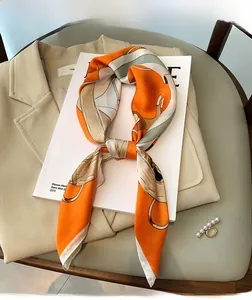 Detail of silk-like satin scarf with orange abstract print and equestrian chain pattern