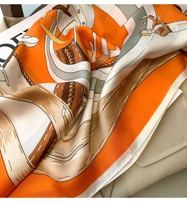 Detailed view of glossy satin scarf with geometric pattern draped on a bag