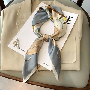 French style geometric print silk scarf tied as a bow on a beige blazer background