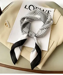 Close-up of a black and white geometric silk scarf draped on a chic magazine