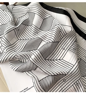Macro view of silky black and white geometric pattern scarf draped on a fashion magazine